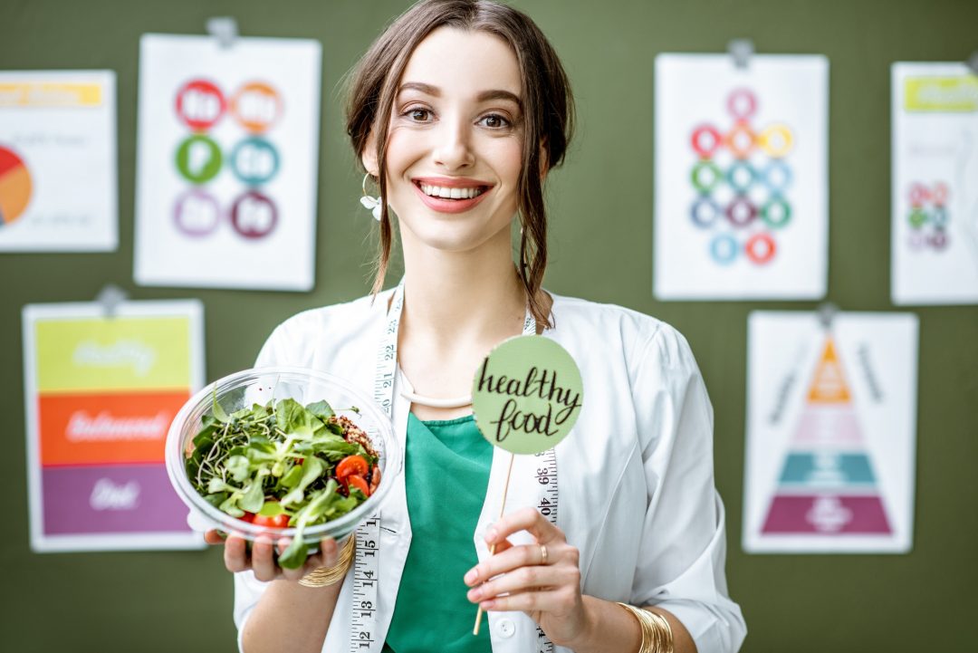 portrait of a woman dietitian with schemes on the topic of nutrition